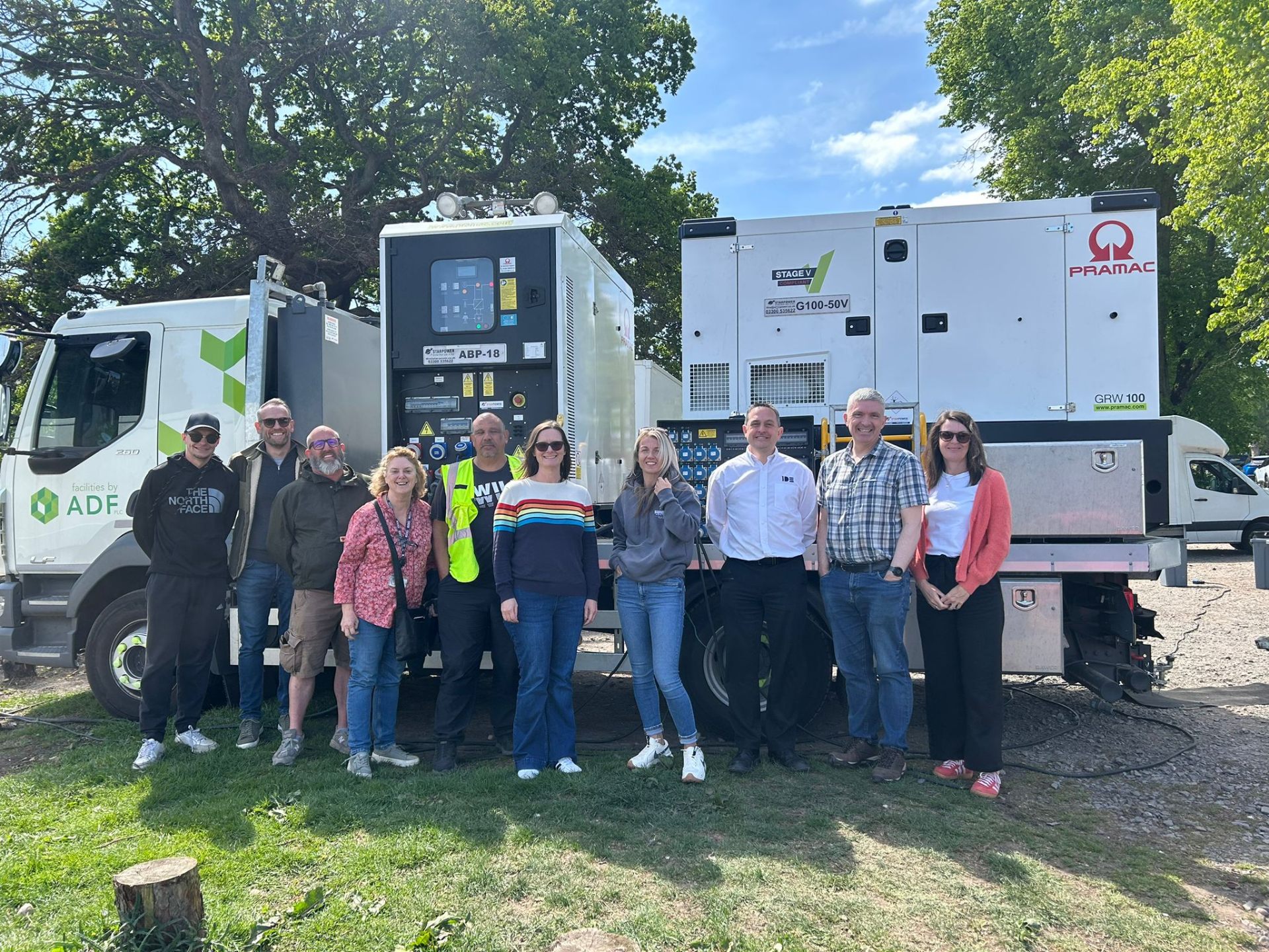 Production team standing in front of a hybrid battery unit and Stage V generator on location.